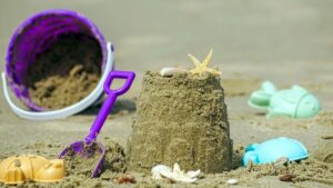 Sandspielzeug und eine Sandburg am Strand