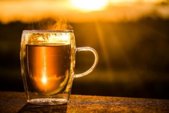 dampfende Teetasse vor Sonnenuntergang